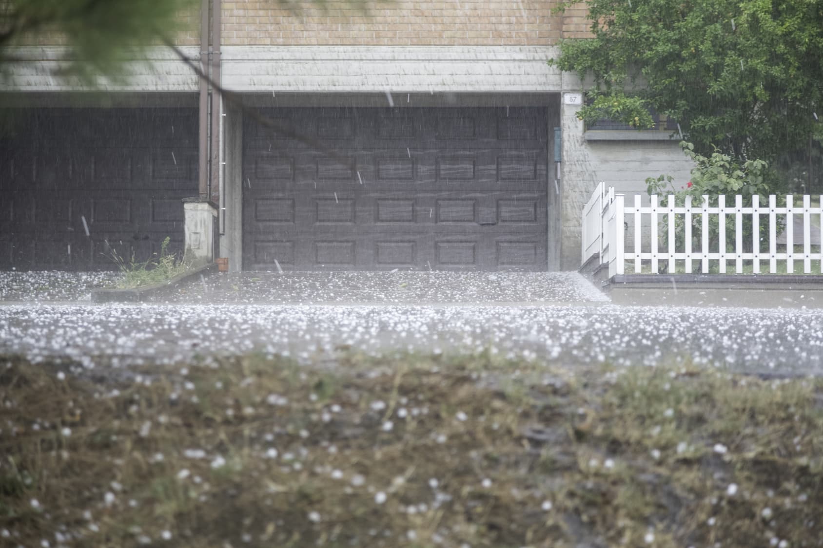 Hail falling from the sky in front of a house